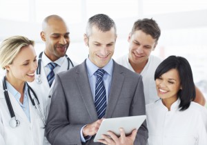A happy medical team gather around a mature administrator using a digital tablet